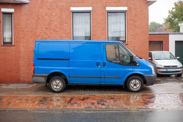 Cuxhaven, Aşağı Saksonya, Almanya. 23 Temmuz 2023 'te. Mavi eski Ford Transit teslimat minibüsü yerleşim yerindeki bir evin önüne park edilmiş.