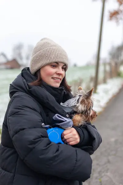 Young woman with a Yorkshire Terrier dog on a walk in winter