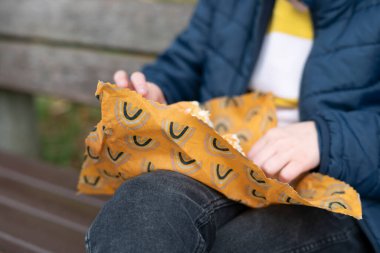 Parktaki bankta oturan ve patlamış mısır yiyen genç bir kadın..