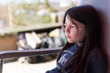 Gözlüklü güzel bir kızın portresi. Yaz bahçesindeki bankta oturuyor.