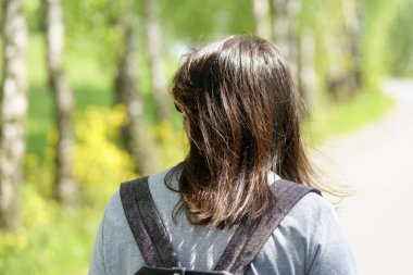 Sırt çantalı genç bir kadının parkta yürüyüşünün arka planı.