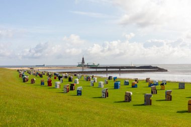 Almanya 'nın Cuxhaven limanındaki yeşil bir çimenlikteki plaj kulübelerinin panoramik fotoğrafı. Yazın deniz kıyısında