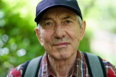 Başlık ve ekose gömlekli yaşlı bir adamın portresi.