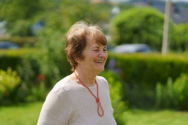 Arka bahçede sırıtan boncuklu yaşlı kadın.