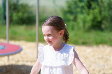 Küçük tatlı anaokulu kızı sıcak bir yaz gününde oyun parkında bir dişi eksik. Güneşin altında çocuk oyunları