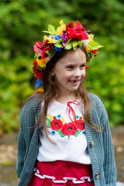 Geleneksel Ukrayna başlığı ve bluzu giymiş gülümseyen genç bir kız güneşli bir yaz gününün tadını çıkarıyor..