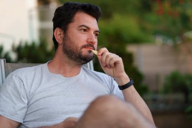 Yalnız, üzgün, ciddi, sakallı, orta yaşlı bir adam gün batımında dışarıda oturuyor. Tek yaşam konsepti