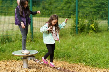 İki küçük kız çocuk parkında oynuyorlar. İpte dengede duran çocuklar. Mutlu çocukluk kavramı
