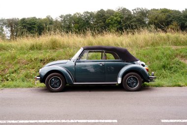 Iserlohn Gruermannscheide, NRW, Almanya. 13 Temmuz 2024. Yol kenarında eski bir Volkswagen Beetle arabası bir tarlanın arka planına karşı. Eski zamanlayıcı çalışıyor.