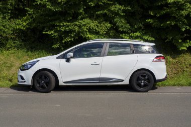 Iserlohn Gruermannscheide, NRW, Almanya. 13 Temmuz 2024. Beyaz Renault Clio yolun kenarında. Aile arabası seyahatte.