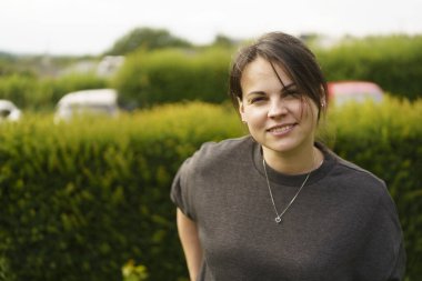 Genç, gülümseyen, saçları toplayan ve yazın arka bahçede kazak giyen güzel bir kız. Mutlu bekar yaşam konsepti