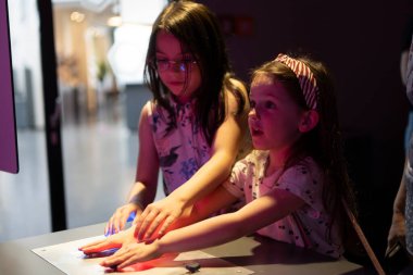 İki güzel kız öğrenci şaşkınlık ve ilgiyle müzeye bakıyor. Çocuk eğitimi konsepti