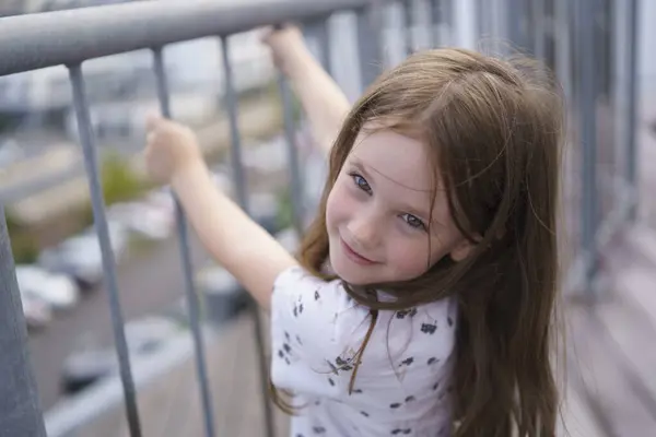 stock image A small, beautiful schoolgirl missing one front tooth hung on the railing. Child health concept