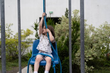 Küçük bir kız kendini sandalyeye oturtmaya çalışırken halat çekiyor. Deneysel çocuk eğitimi kavramı.