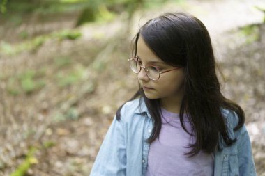 Yazın ormanda yürüyen gözlüklü tatlı bir kız. Doğayla birlik kavramı