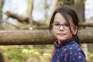 Little girl with glasses in the mountains. Little traveler on a hike. Concept of children's wanderings clipart