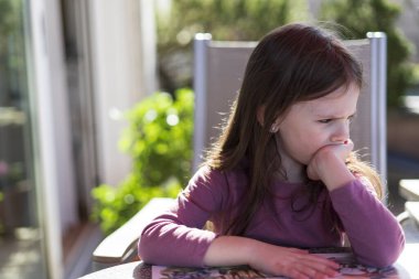 Tatlı küçük bir kız terasta arka bahçede bir masada otururken kitap okuyor. Eğitimsel ev kavramı