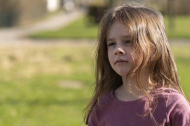 Küçük sevimli kızıl saçlı bir kız yeşil çimenlerin arkasında dikilirken annesinin elini tutuyor. Aile ilişkileri kavramı