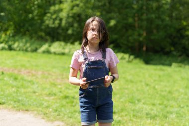 Parlak yeşil arka planda gözlüklü güzel bir kız. Mutlu çocukluk kavramı açık havada