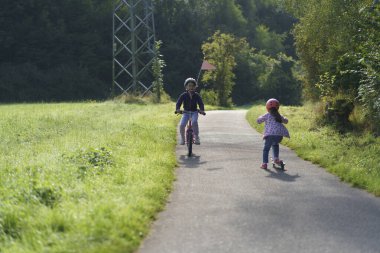 Parkta bisiklet süren gözlüklü ve kasklı tatlı bir kız. Çocuk eğlencesi kavramı