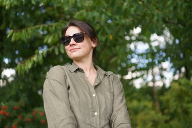 Güneş gözlüklü esmer kız ve yaz çiftliği geçmişinde poz veren yarım düğmesiz gömlek. Tarım, güzellik, bilgi ve seyahat kavramı