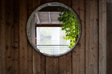 Round window in a wooden wall. Concept of geometric shapes in construction clipart