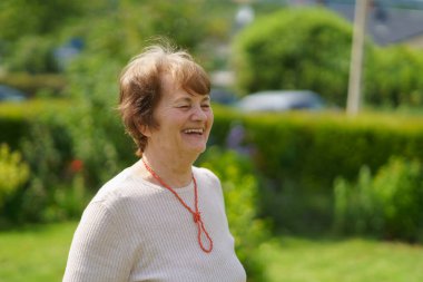 Yazın arka bahçede gülümseyen yaşlı bir kadın. Aktif ve sağlıklı yaşlılık kavramı