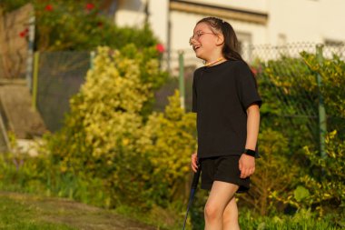 Yazın kız kardeşiyle arka bahçede badminton oynayan gözlüklü siyah saçlı küçük kız. Neşeli, aktif, sağlıklı çocuk kavramları