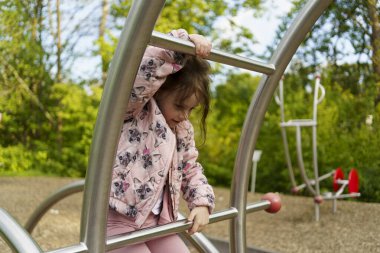 Yazın çocuk parkına tırmanan uzun saçlı küçük kız. Sağlıklı aktif yaramaz çocuk konsepti