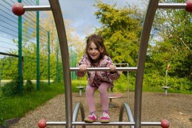 Yazın çocuk parkına tırmanan uzun saçlı küçük kız. Sağlıklı aktif yaramaz çocuk konsepti