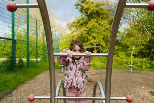 Yazın çocuk parkına tırmanan uzun saçlı küçük kız. Sağlıklı aktif yaramaz çocuk konsepti