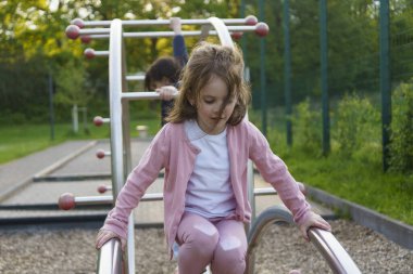 Yazın çocuk parkına tırmanan uzun saçlı küçük kız. Sağlıklı aktif yaramaz çocuk konsepti