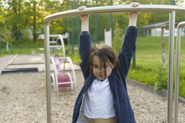 Yazın parka tırmanan gözlüklü tatlı bir kız. Sağlıklı, aktif, neşeli çocuk kavramı