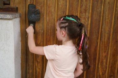 Ahşap kapının yanında duran rastalı küçük şirin kız. Sağlıklı aktif çocuk kavramı
