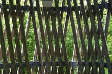 Wooden lattice fence. Concept of fence made of natural materials of interesting shape clipart