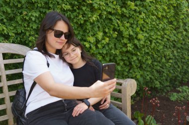 Anne ve kızı yazın açık havada cep telefonuyla selfie çekiyorlar. Modern dijital yaşam kavramı