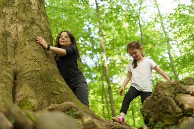 Aktif neşeli kız yaz ormanında kayalara tırmanıyor. Sağlıklı aktif sporcu çocuk kavramı