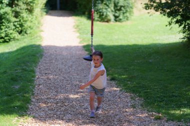 Ön dişleri olmayan küçük tatlı kız yaz aylarında halat parkında kayarak kayıyor. Aktif, sağlıklı, neşeli çocuk kavramı