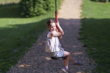 Ön dişleri olmayan küçük tatlı kız yaz aylarında halat parkında kayarak kayıyor. Aktif, sağlıklı, neşeli çocuk kavramı