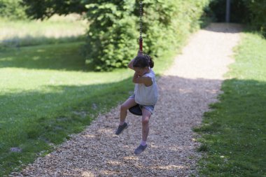 Ön dişleri olmayan küçük tatlı kız yaz aylarında halat parkında kayarak kayıyor. Aktif, sağlıklı, neşeli çocuk kavramı