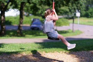 Ön dişleri olmayan küçük tatlı kız yaz aylarında halat parkında kayarak kayıyor. Aktif, sağlıklı, neşeli çocuk kavramı
