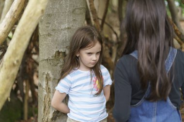 Two girls quarreling in the forest. Concept of complex relationships between children clipart