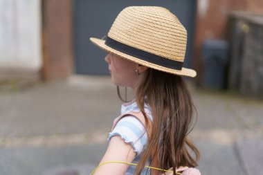 Sırt çantalı saman şallı küçük tatlı kız yazın seyahat ediyor. Bir çocuğun neşeli, aktif, sağlıklı çocuğu kavramı