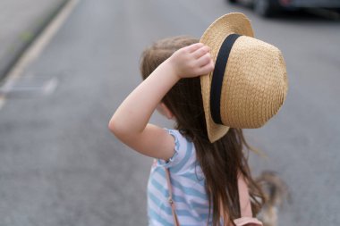 Sırt çantalı saman şallı küçük tatlı kız yazın seyahat ediyor. Bir çocuğun neşeli, aktif, sağlıklı çocuğu kavramı