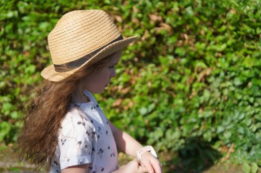 Sırt çantalı saman şallı küçük tatlı kız yazın seyahat ediyor. Bir çocuğun neşeli, aktif, sağlıklı çocuğu kavramı