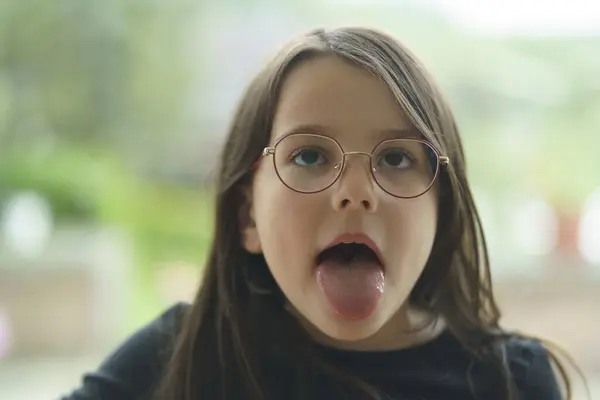 Kocaman şeffaf bir pencerenin önünde tüm dişleriyle gülümseyen küçük tatlı kız. Sağlıklı çocuk dişleri kavramı