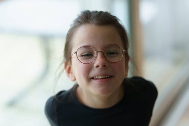 Büyük pencerenin yanında duran gözlüklü küçük tatlı kız. Akıllı bilinçli çocuk kavramı