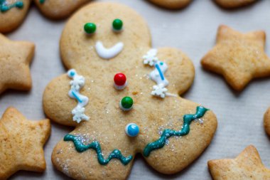 Diğer şekerlerle çevrili küçük süslü bir Noel zencefilli kurabiye adam. Noel pastası