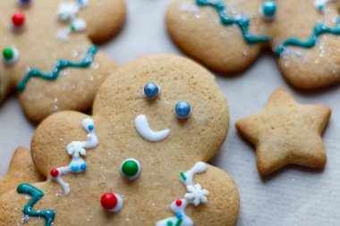 Diğer şekerlerle çevrili küçük süslü bir Noel zencefilli kurabiye adam. Noel pastası