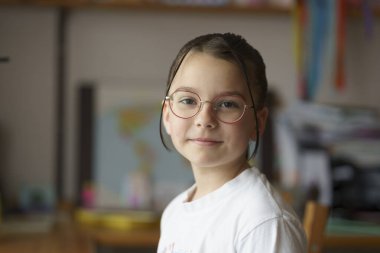 Gözlüklü, saç stili güzel bir genç kız. Arka planda bulanık çocuk odası. Çocukluk kavramı